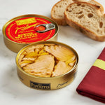 A tin can of Los Peperetes Bonito del Norte white tuna in olive oil, with the tuna visible inside the open can, placed on a textured surface.