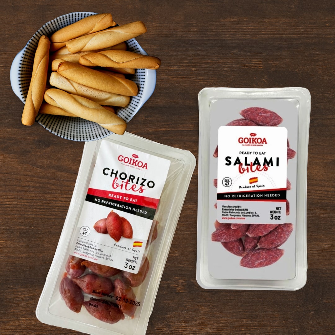 Two packages of Goiko Salami Bites and Chorizo Bites on a wooden surface with bread sticks.
