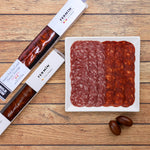 Fermin salami and pepperoni on a wooden surface with packaging.