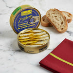 A tin can of Los Peperetes small sardines in olive oil, with the sardines visible inside the open can, placed on a wooden surface.