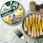 Open can of sardines in truffle oil with 'La Curiosa' packaging on a marble surface.
