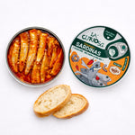 Tin of sardines with a decorative label and slices of bread on a white background