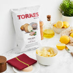 Torres foie gras-flavored potato chips packaging on a table with lemon slices and a plant.