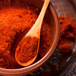 a bowl with paprika powder and a wooded spoon