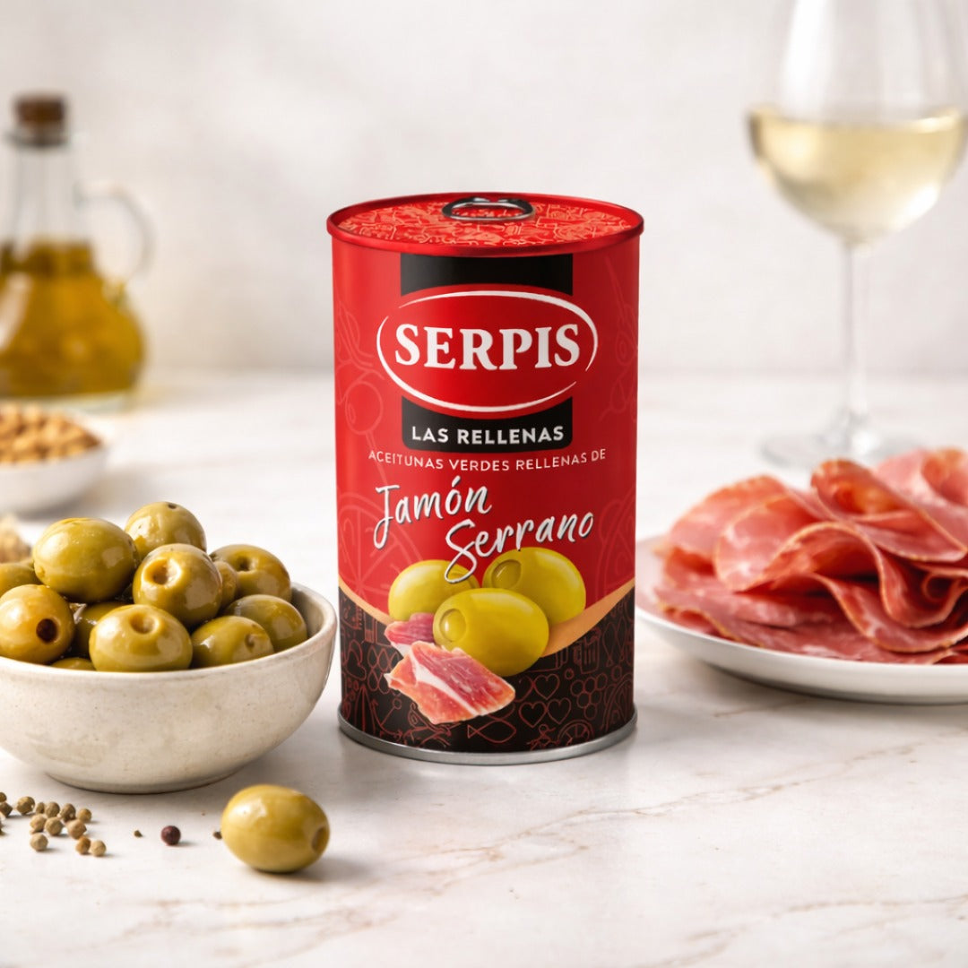 Serpis can of stuffed olives with a plate of cured meat and bowl of olives on a table.