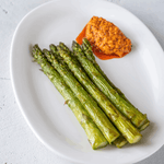 grilled green asparagus with a orange sauce on a white plate