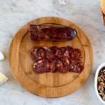 Wooden cutting board with sliced iberico chorizo on a red surface