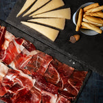 Platter with sliced meats and cheese on a dark surface