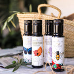Four bottles of olive oil with decorative labels on a table with a woven basket in the background.