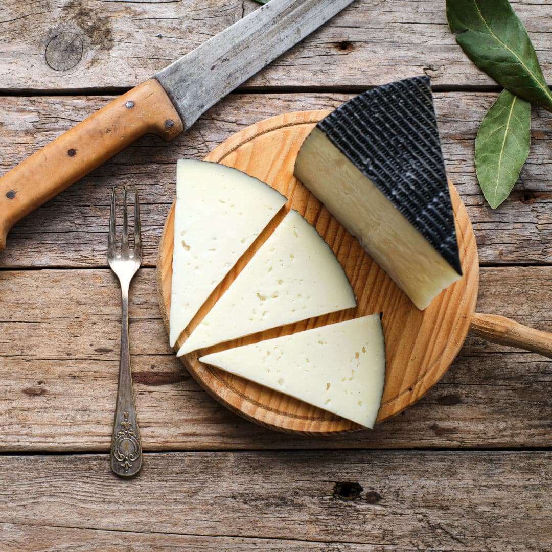 Wedge of cheese on a wooden table with a fork