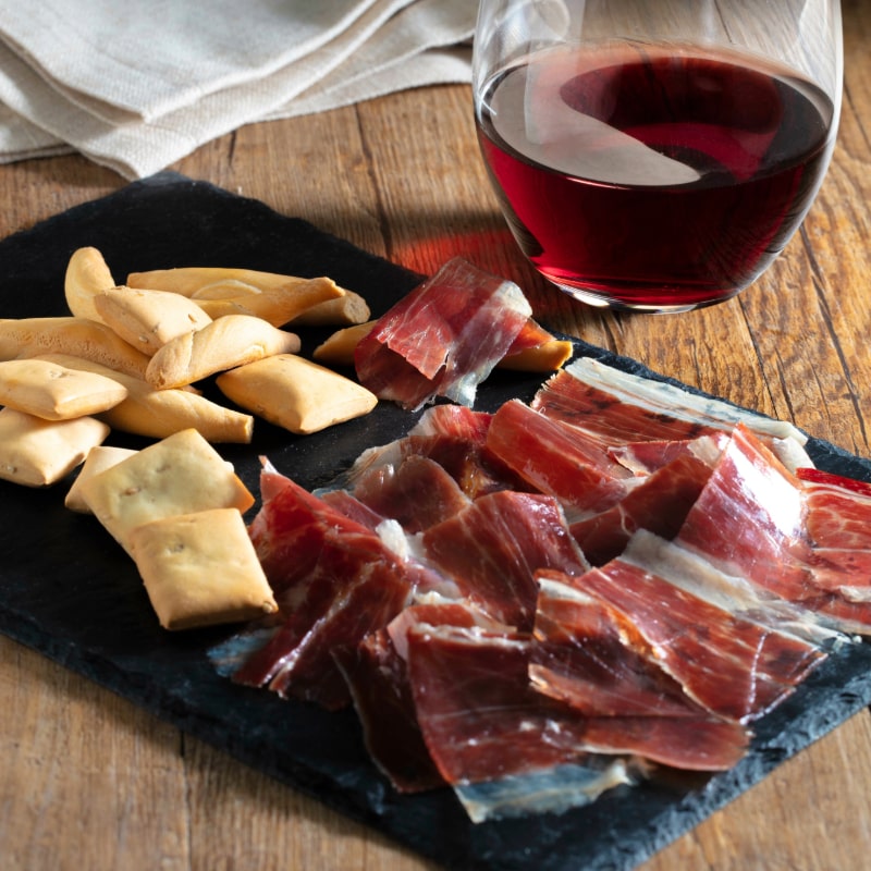 a glass of red wine with jamon iberico