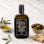 Bottle of Pons olive oil with olive leaves, bread, and olives on a white background