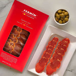 a package of Lomo Serrano Fermin and a plate with sliced Lomo and Olives