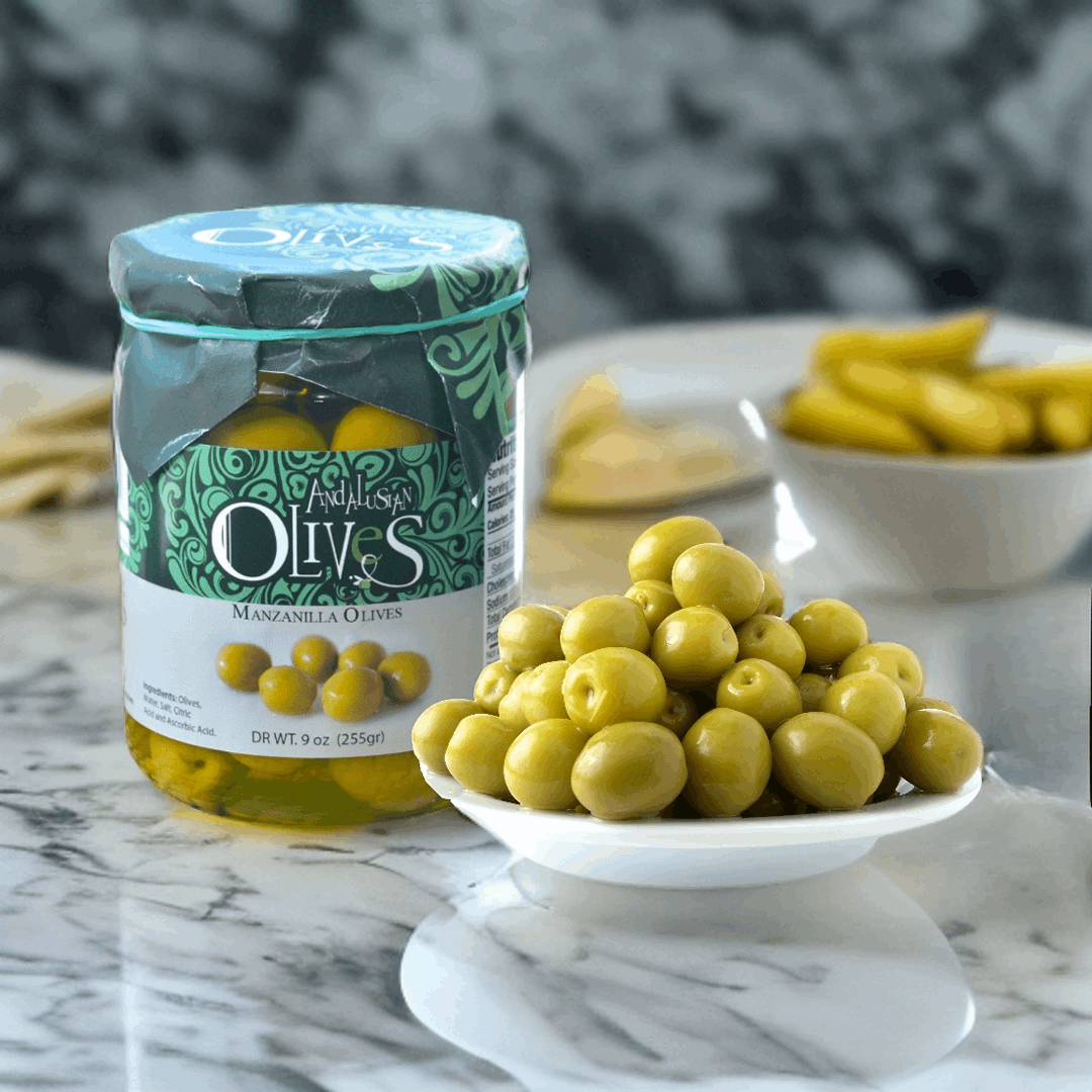a jar of olives en a white plate with green olives