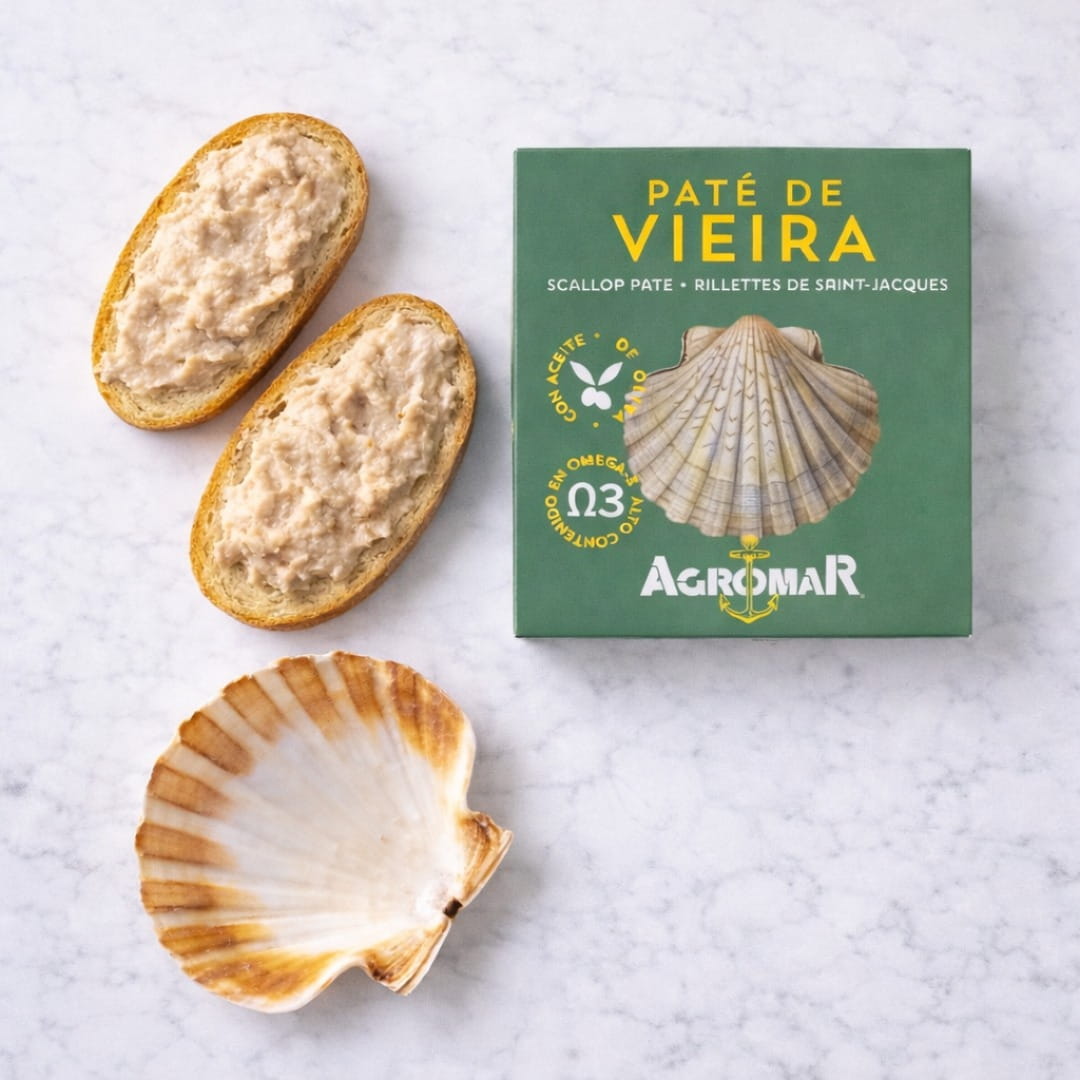 Scallops pate on bread with a green Agromar packaging on a white marble surface