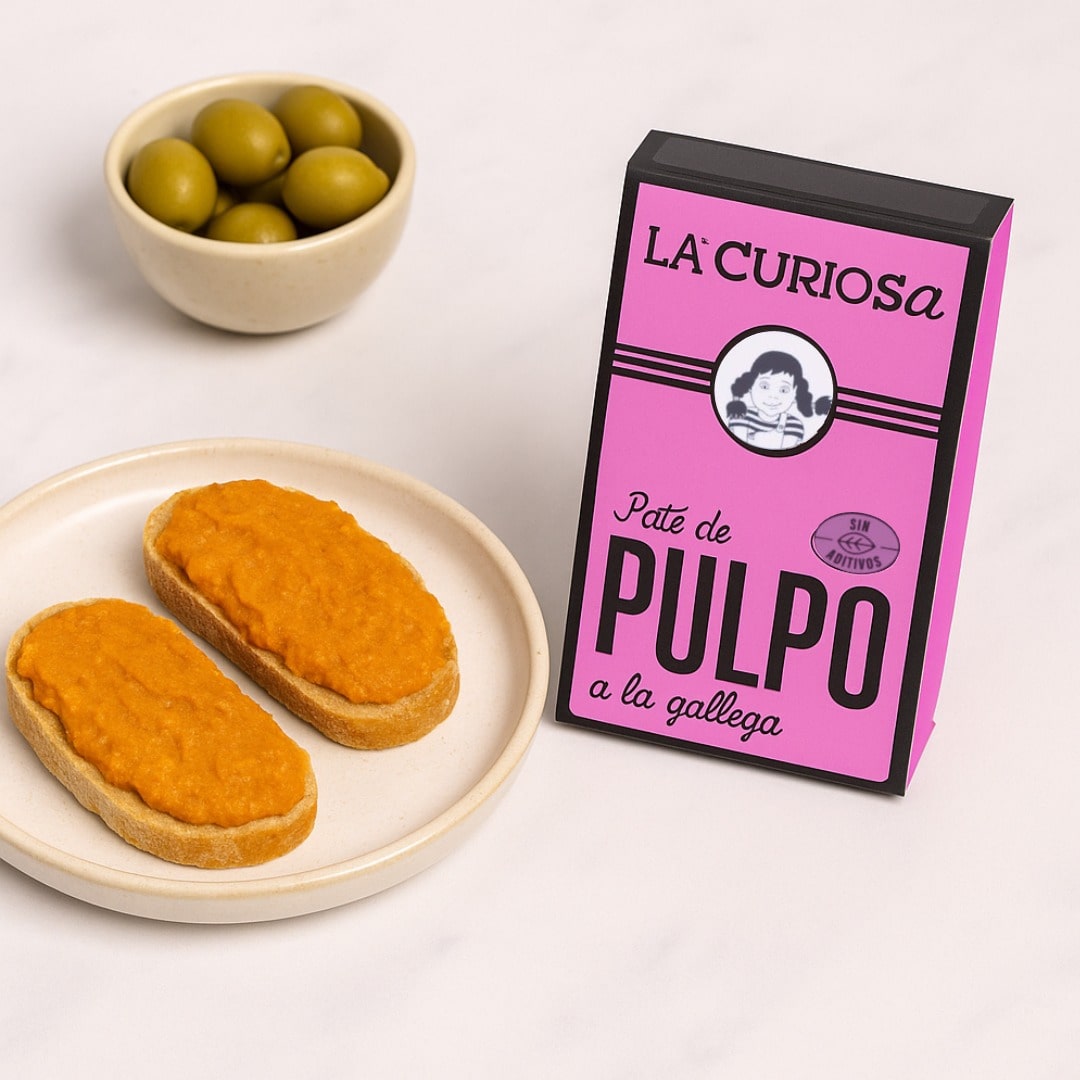 Pink packaging of 'La Curiosa' octopus pate on a white plate with bread and olives.