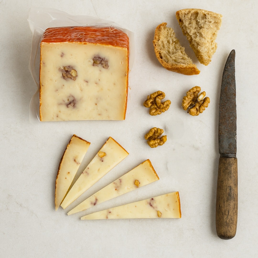 Cheese with slices, walnuts, and a knife on a light surface