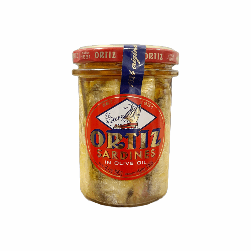 a glass jar with with a red sticker on the front with canned sardines inside