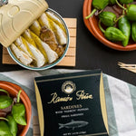 Packaged sardines with pimientos on a table with fresh pimientos.