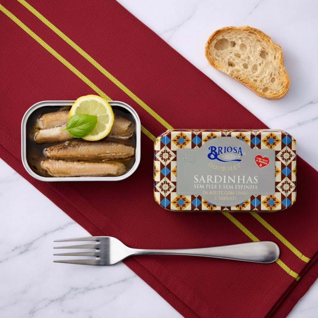 Tin of sardines with a slice of bread and lemon on a marble surface