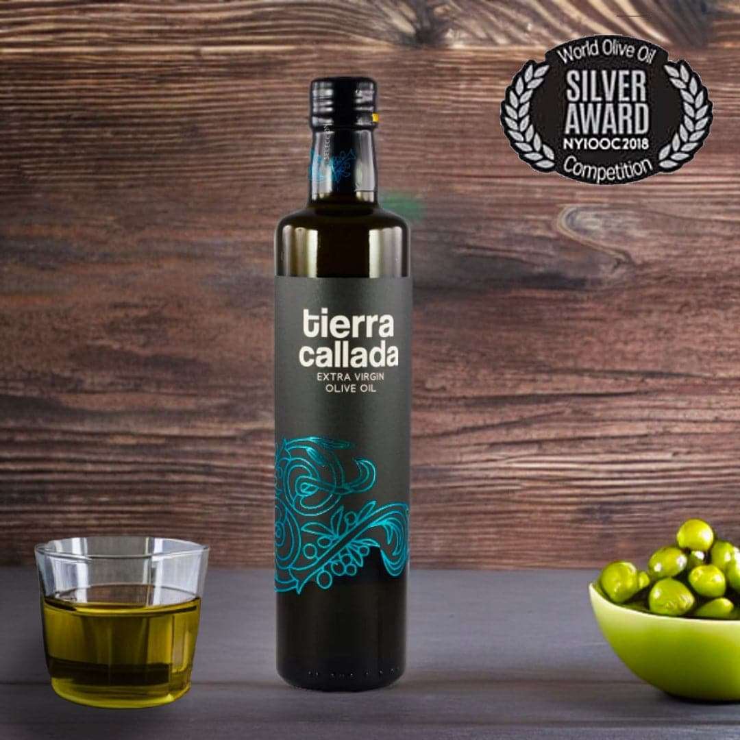 a bottle of olive oil and a glass of olive oil and some green olives